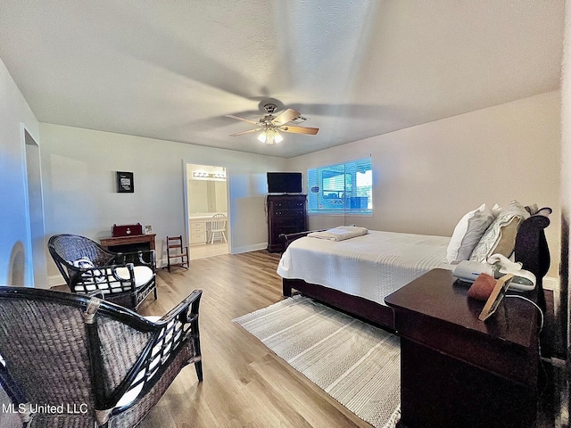 bedroom with ensuite bathroom, baseboards, a ceiling fan, and light wood-style floors