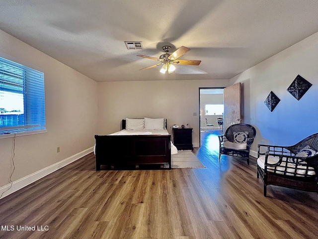 bedroom featuring a ceiling fan, visible vents, baseboards, and wood finished floors