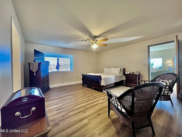 bedroom featuring visible vents, multiple windows, baseboards, and wood finished floors