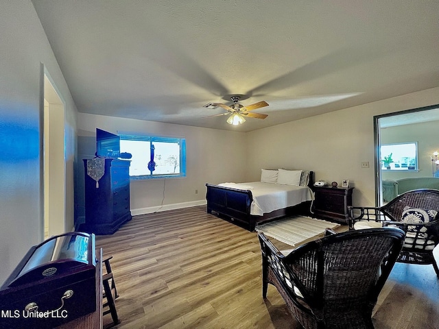 bedroom featuring ceiling fan, baseboards, and wood finished floors