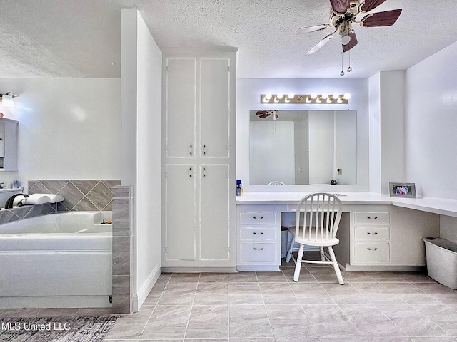 bathroom featuring a ceiling fan, a tub to relax in, vanity, and a textured ceiling