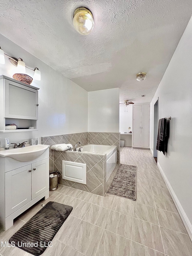 full bathroom featuring tile patterned flooring, vanity, a textured ceiling, and a bath