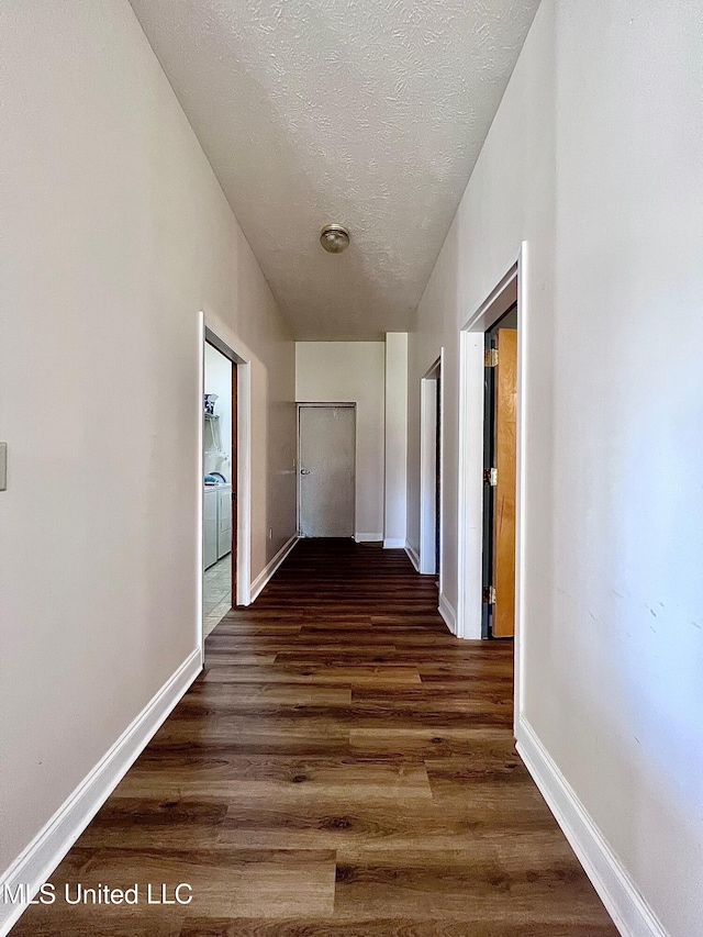 hall featuring a textured ceiling, baseboards, and dark wood-type flooring