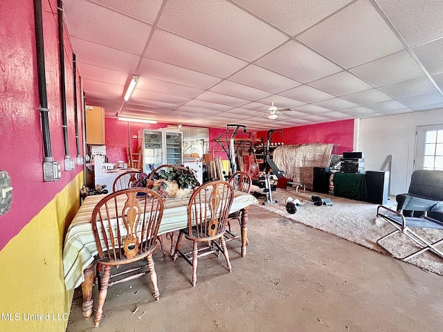 dining space with concrete floors and a drop ceiling