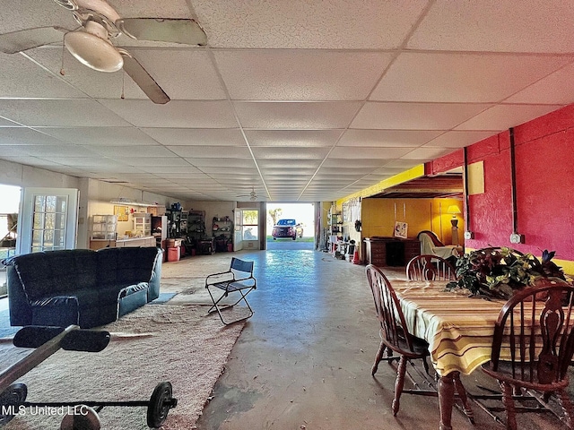 dining room with a drop ceiling, unfinished concrete flooring, and ceiling fan