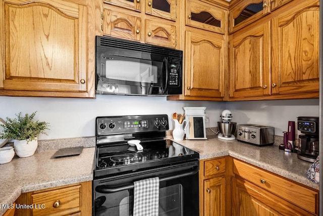 10840 Ala Moana St, Diamondhead, MS 39525 - kitchen featuring black appliances, brown cabinetry, light countertops, and glass insert cabinets