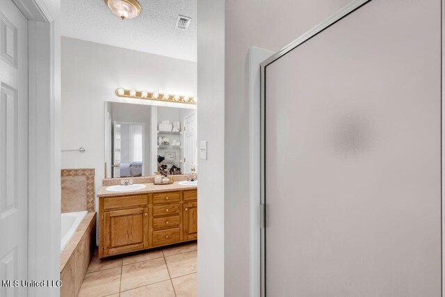 10840 Ala Moana St, Diamondhead, MS 39525 - ensuite bathroom featuring a garden tub, tile patterned flooring, a shower stall, double vanity, and a textured ceiling