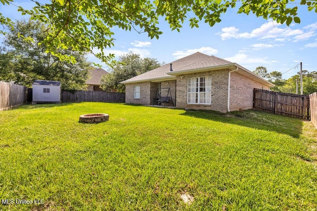 10840 Ala Moana St, Diamondhead, MS 39525 - back of house with an outdoor fire pit, brick siding, a storage shed, an outdoor structure, and roof with shingles