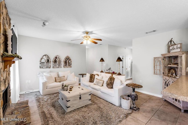 10840 Ala Moana St, Diamondhead, MS 39525 - living area with a ceiling fan, tile patterned floors, a textured ceiling, and a fireplace with raised hearth