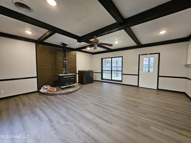 unfurnished living room with ceiling fan, visible vents, wood finished floors, and a wood stove