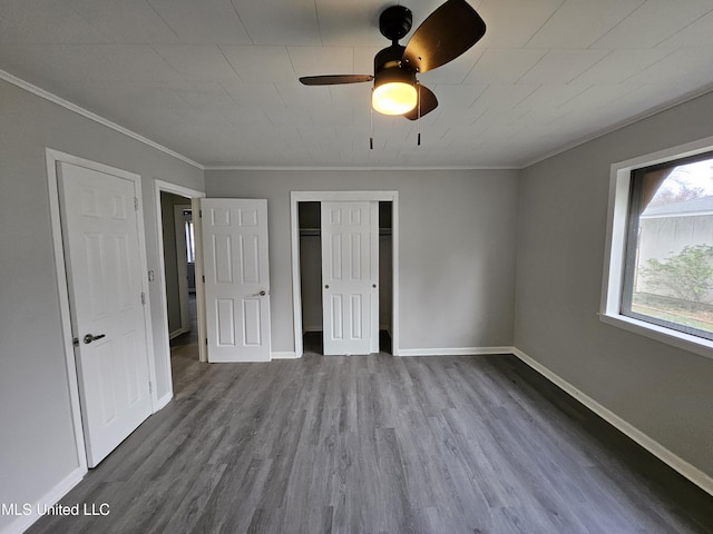 unfurnished bedroom featuring a closet, crown molding, wood finished floors, baseboards, and ceiling fan