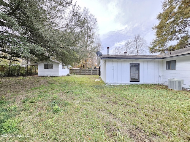view of yard featuring fence, cooling unit, and an outbuilding