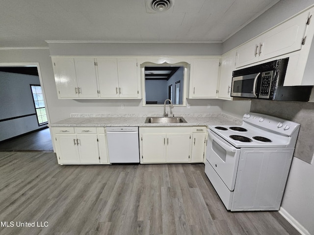 kitchen with visible vents, crown molding, a sink, light wood finished floors, and white appliances