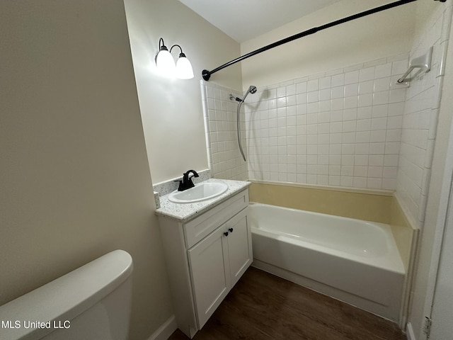 full bathroom with vanity, tiled shower / bath, hardwood / wood-style floors, and toilet