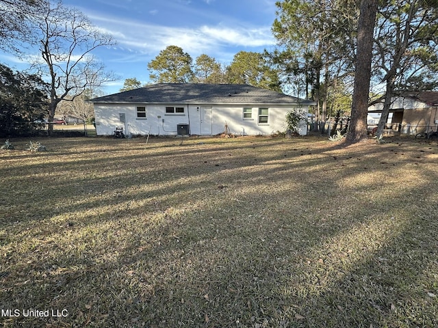 back of property with central AC and a yard