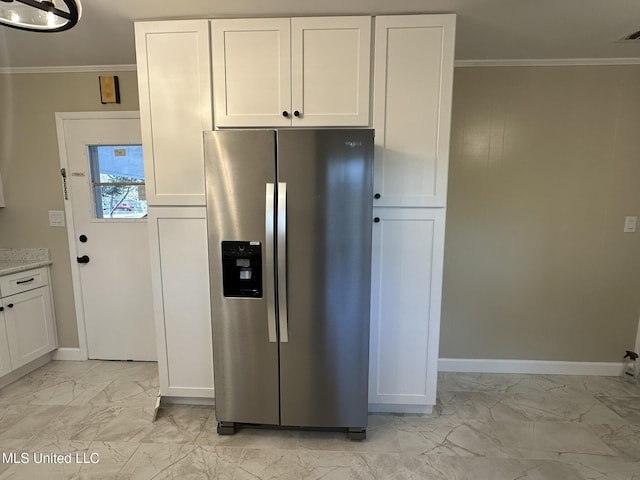 kitchen with stainless steel fridge, ornamental molding, and white cabinets