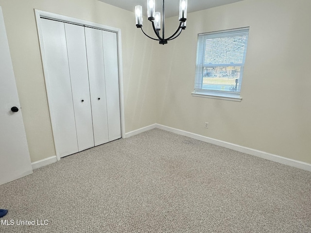 unfurnished bedroom with carpet floors, a chandelier, and a closet