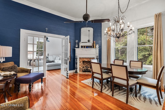 dining room featuring a notable chandelier, a brick fireplace, and hardwood / wood-style floors