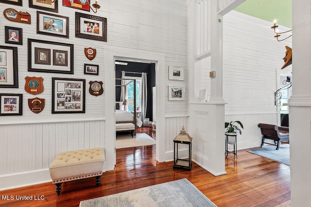 interior space with a towering ceiling, ornate columns, wood-type flooring, and wooden walls