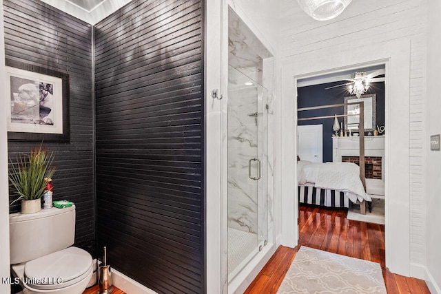 bathroom featuring toilet, a shower with shower door, and wood-type flooring