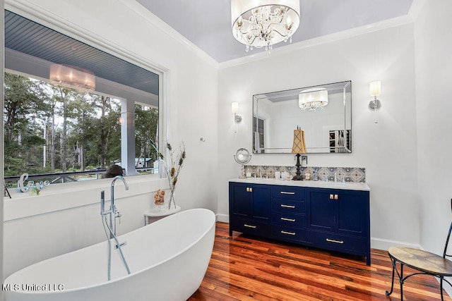 bathroom featuring a tub, hardwood / wood-style floors, vanity, crown molding, and an inviting chandelier