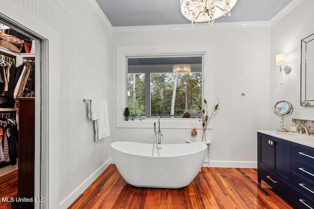 bathroom with an inviting chandelier, hardwood / wood-style flooring, a washtub, vanity, and crown molding