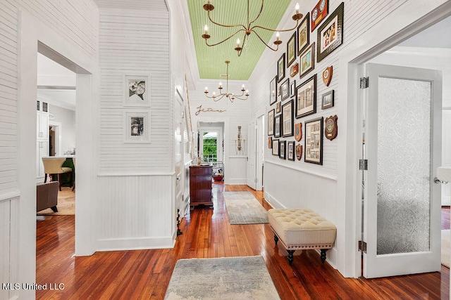 hallway with a towering ceiling, crown molding, a chandelier, and wood-type flooring