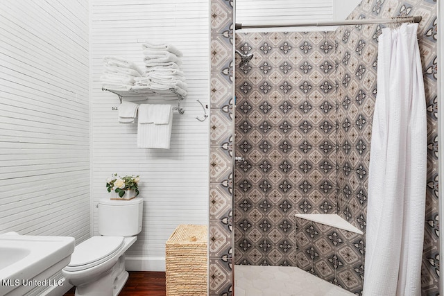 bathroom with hardwood / wood-style floors, a shower with curtain, and toilet