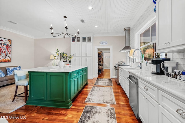 kitchen featuring wall chimney range hood, white cabinetry, a center island, stainless steel appliances, and green cabinets