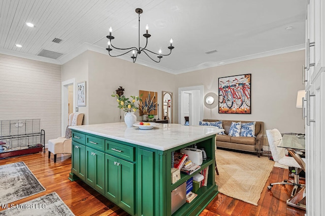 kitchen featuring hanging light fixtures, green cabinets, hardwood / wood-style floors, a center island, and light stone counters