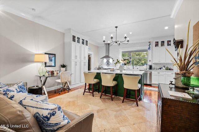 kitchen featuring wall chimney exhaust hood, white cabinetry, a center island, and decorative light fixtures