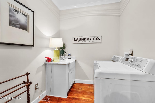 laundry area with ornamental molding, washer and clothes dryer, light hardwood / wood-style flooring, and cabinets