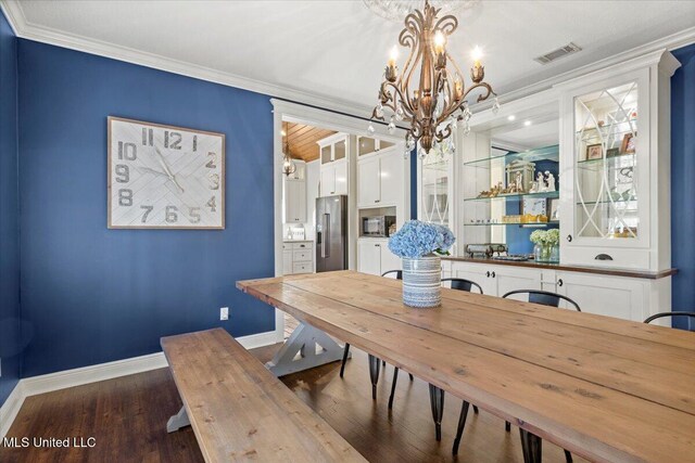 dining room with dark wood-type flooring, crown molding, baseboards, and visible vents