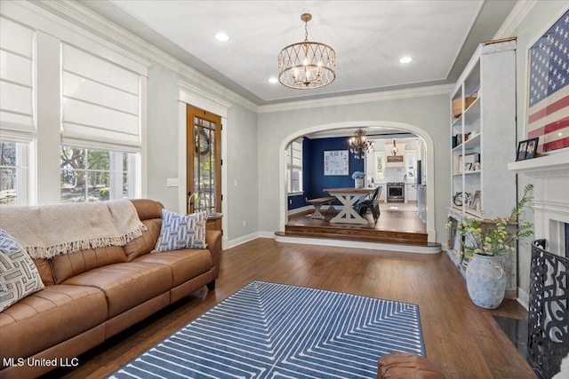 living area with an inviting chandelier, crown molding, wood finished floors, and arched walkways