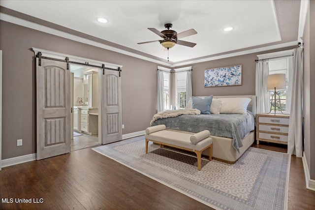 bedroom featuring baseboards, a tray ceiling, ornamental molding, a barn door, and wood finished floors