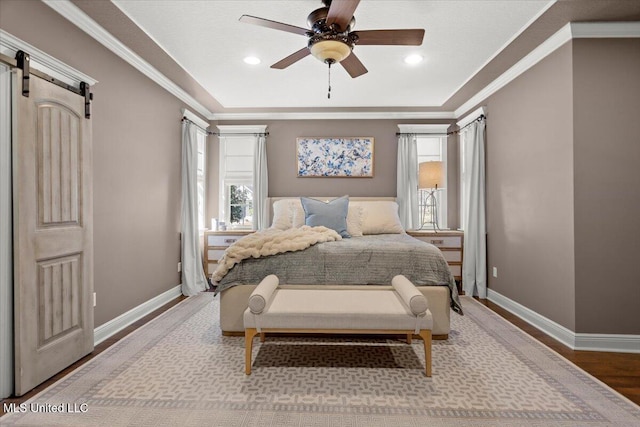 bedroom featuring baseboards, crown molding, a barn door, and wood finished floors