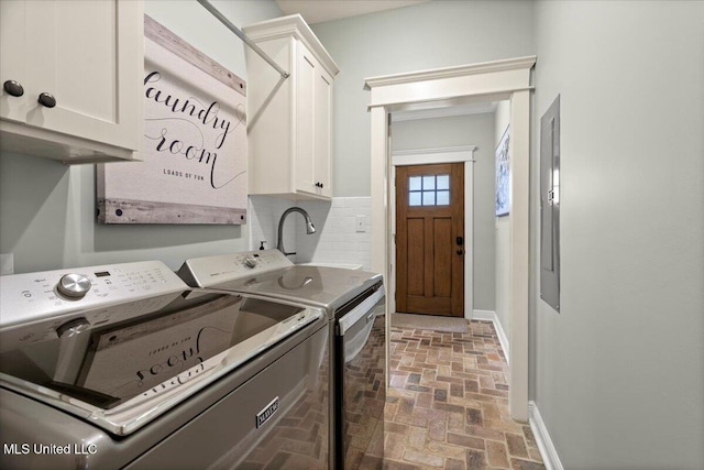 washroom with brick floor, cabinet space, baseboards, and washer and clothes dryer