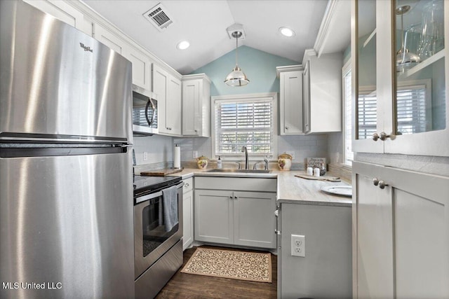 kitchen with visible vents, a sink, tasteful backsplash, stainless steel appliances, and vaulted ceiling