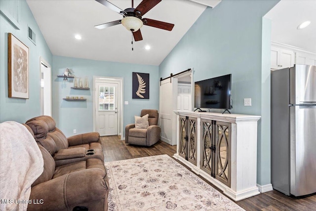 living area featuring ceiling fan, a barn door, visible vents, and dark wood finished floors