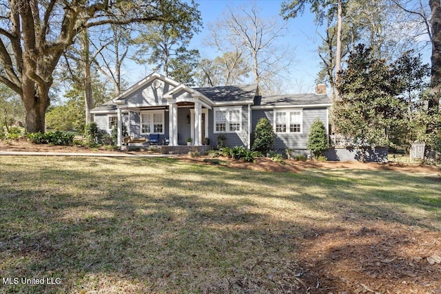 view of front facade with a chimney, a porch, and a front yard