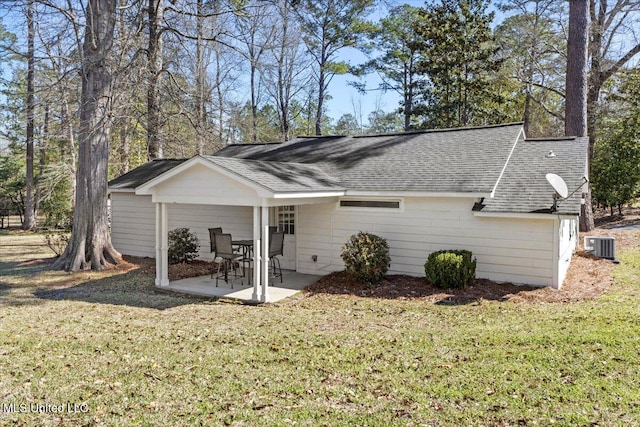 rear view of property with central air condition unit, a lawn, roof with shingles, and a patio area