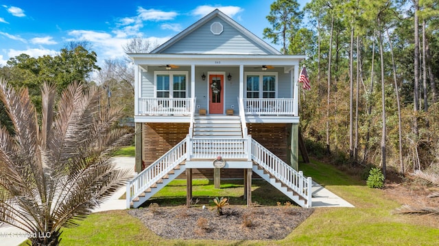 coastal home featuring ceiling fan, a porch, and a front lawn