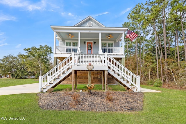 beach home featuring ceiling fan, covered porch, and a front yard