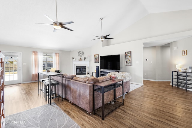 living room featuring wood-type flooring, ceiling fan, and vaulted ceiling