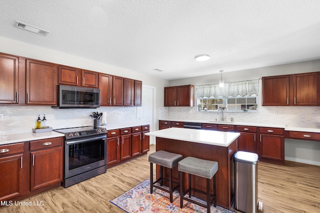 kitchen with pendant lighting, sink, a breakfast bar, stainless steel appliances, and a kitchen island