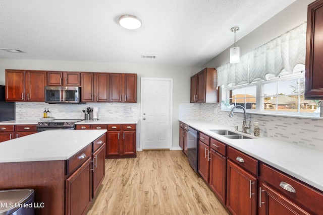 kitchen with sink, hanging light fixtures, stainless steel appliances, tasteful backsplash, and light wood-type flooring