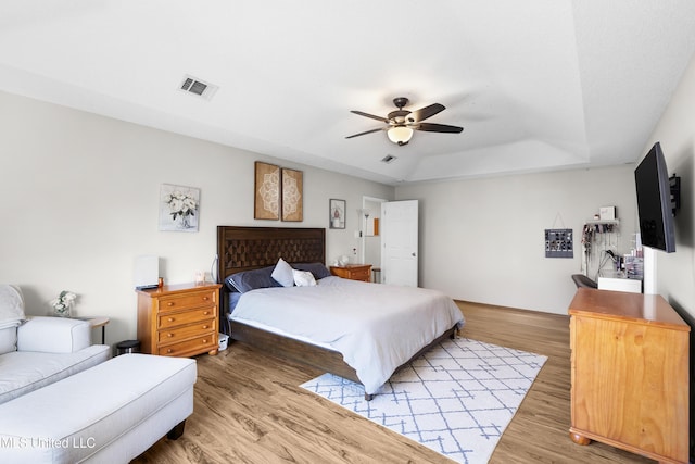 bedroom featuring ceiling fan, a tray ceiling, and hardwood / wood-style floors