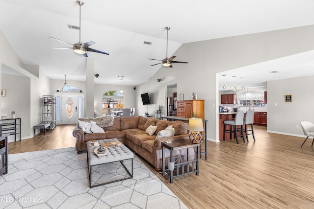 living room with vaulted ceiling, ceiling fan, and light wood-type flooring