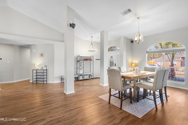 dining area featuring hardwood / wood-style flooring, lofted ceiling, and a notable chandelier