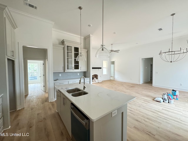 kitchen featuring light wood-style flooring, a sink, visible vents, stainless steel dishwasher, and an island with sink